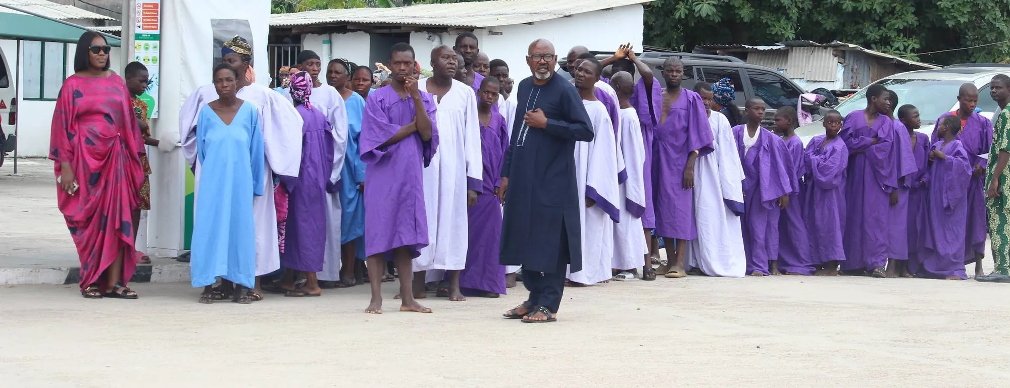 Members in purple and white robes gathered outdoors during an outreach