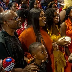 A family worshipping together, with a child holding a small Nigerian flag
