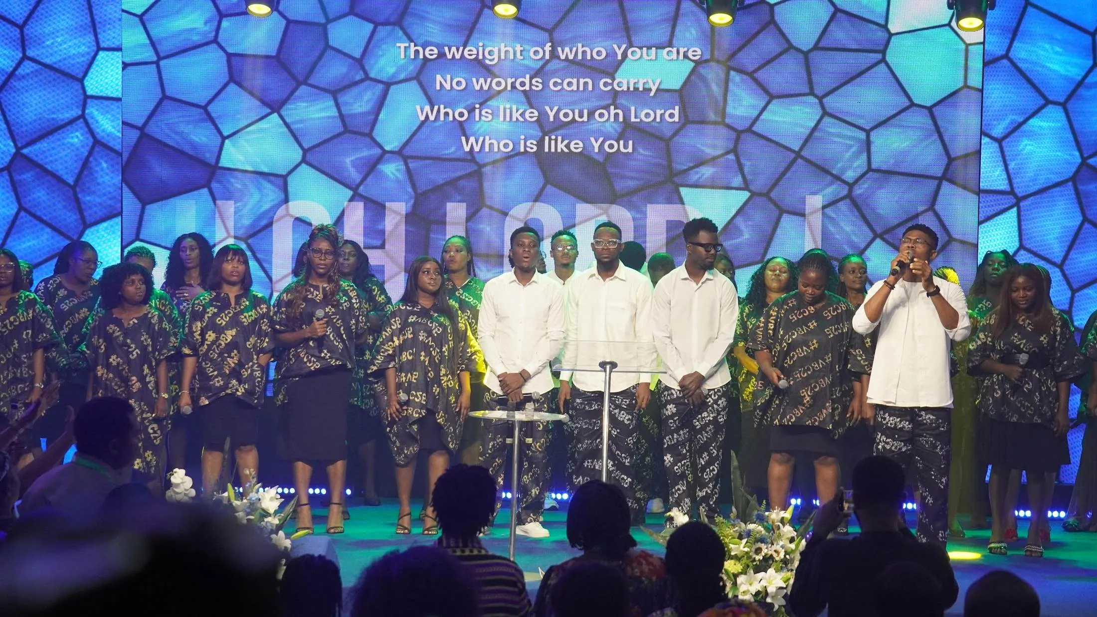 The choir leading worship in front of a stained-glass screen