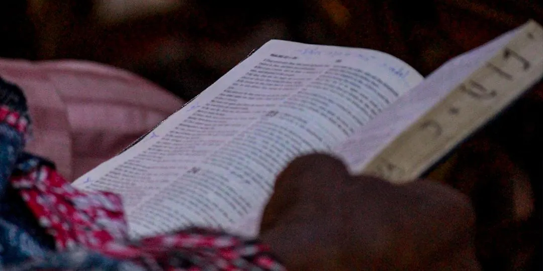 Hands holding an open Bible during a Sabbath service