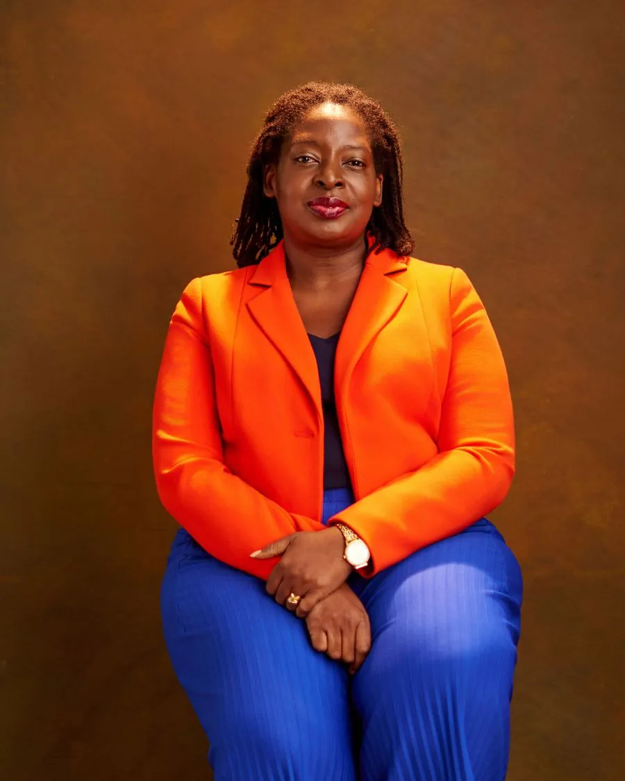 Pastor Bola Ajide in an orange blazer, seated and smiling
