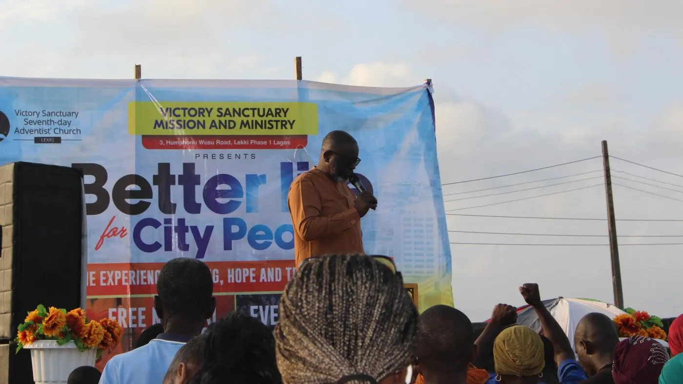 A pastor preaching under a Better Life for City People banner