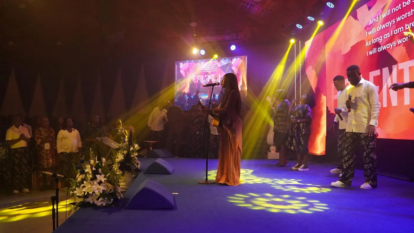 A music minister singing on a stage washed in gold light at VBC 2025
