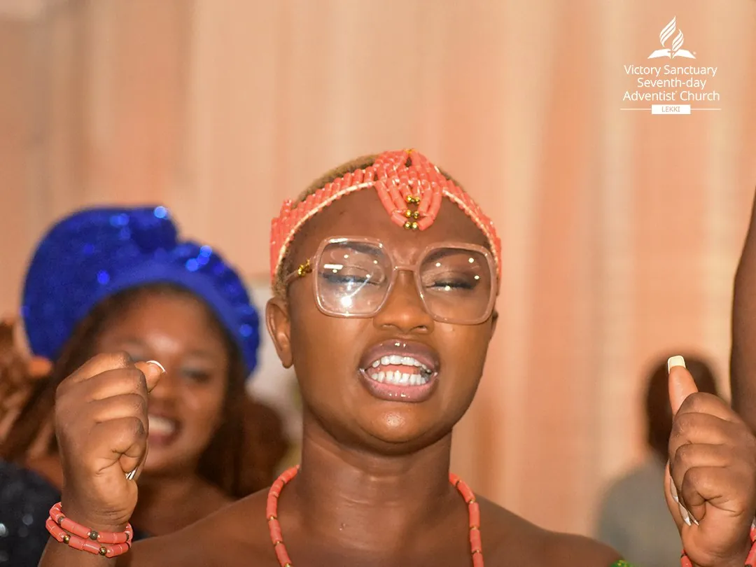 A young woman in coral beads and Igbo attire singing with joy at Yabonupe