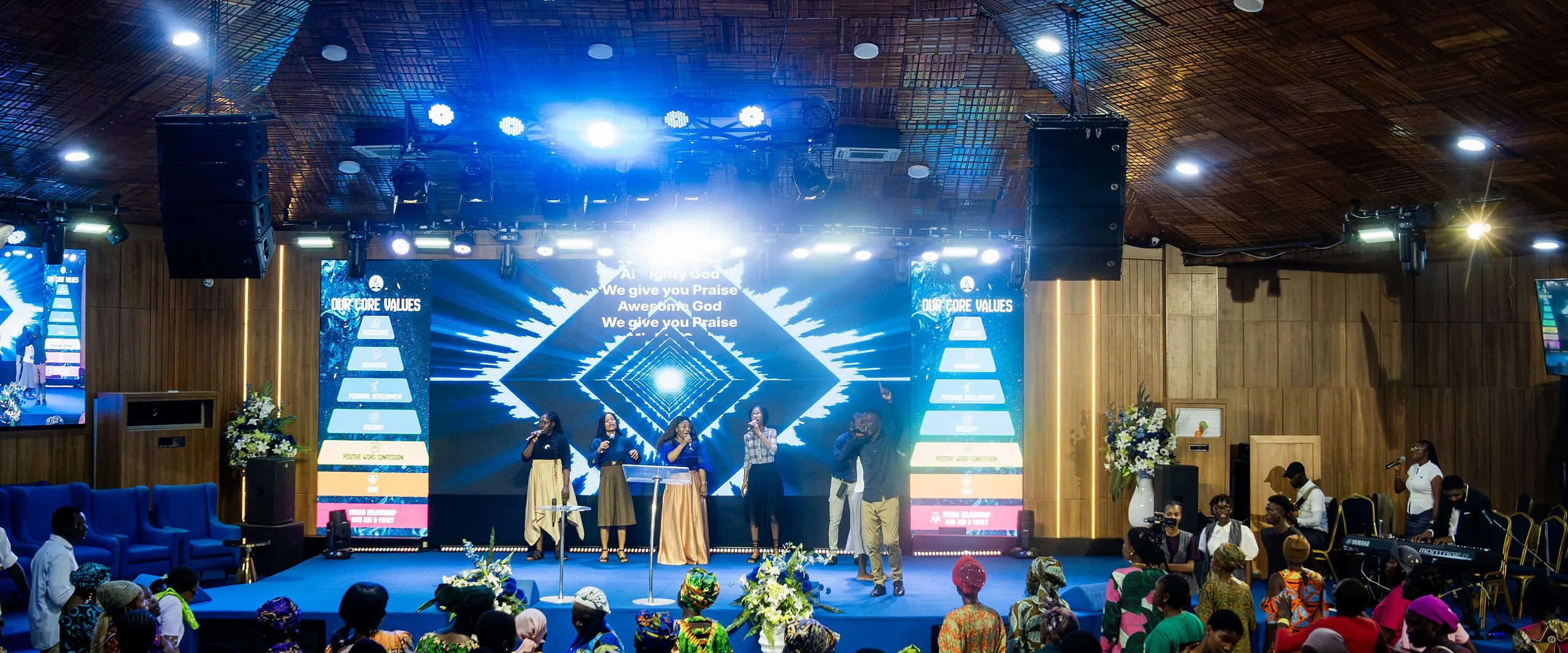 The congregation worshipping in the sanctuary, with the worship team on a stage lit in blue