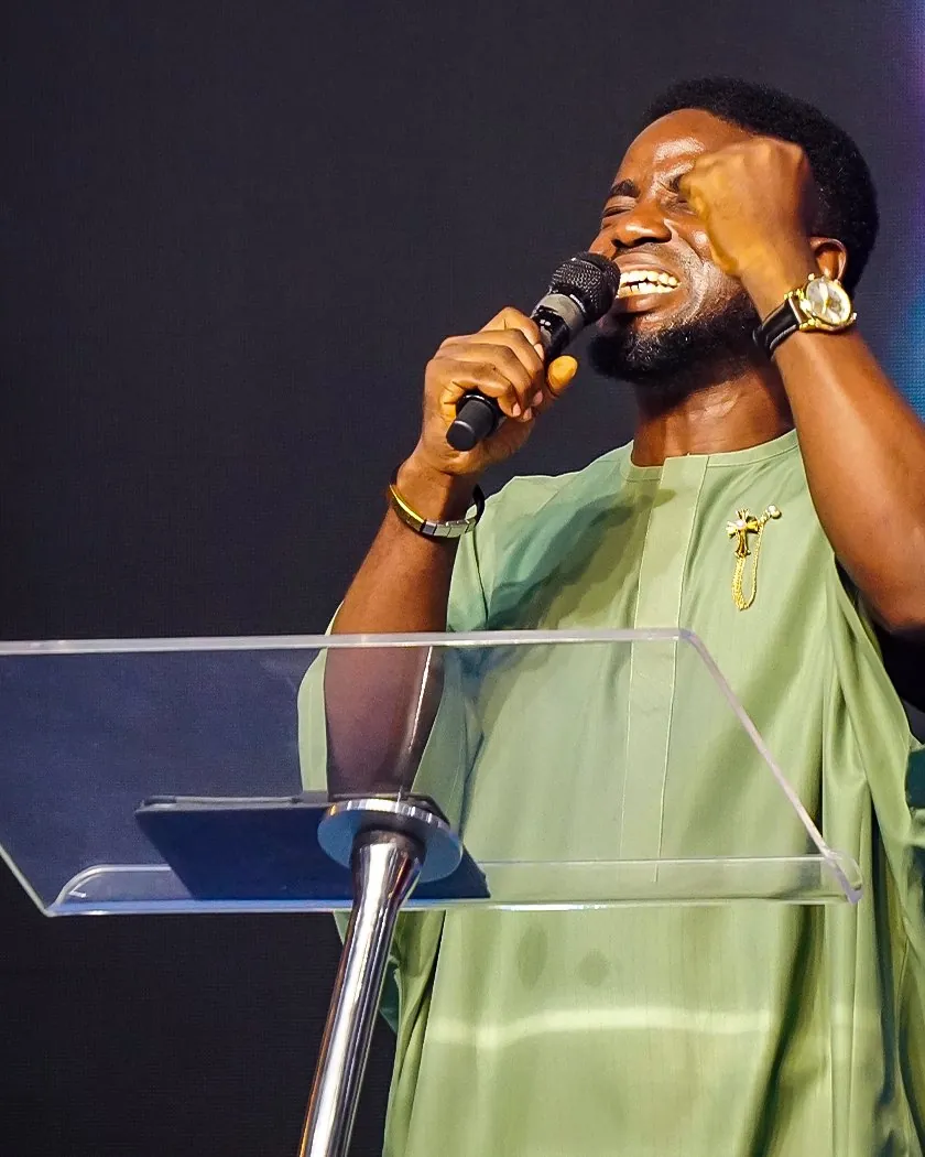 A man in a green outfit leading from the lectern with a microphone