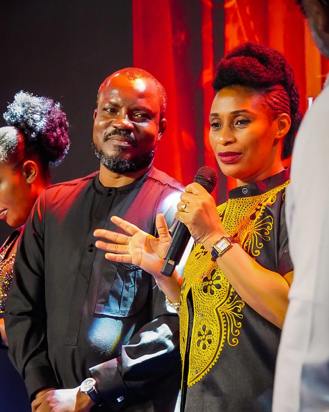A couple sharing from the stage, the wife holding the microphone