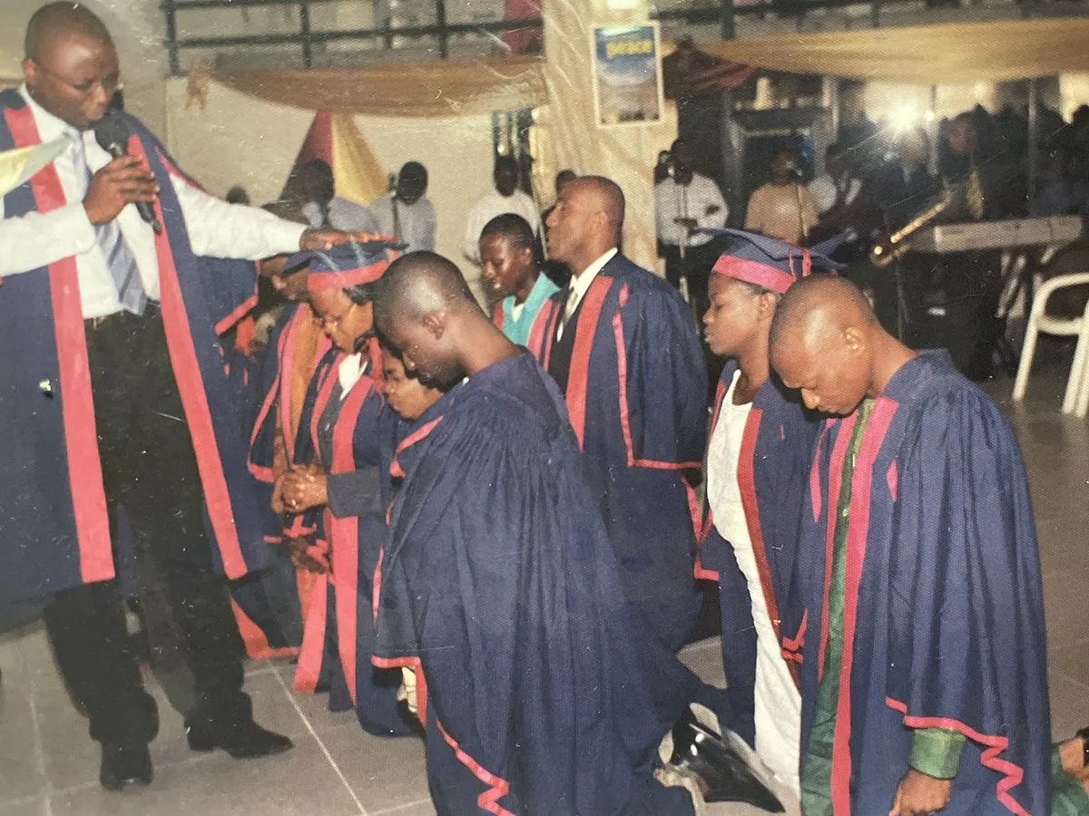 Bible school graduates in gowns kneeling as they are prayed over