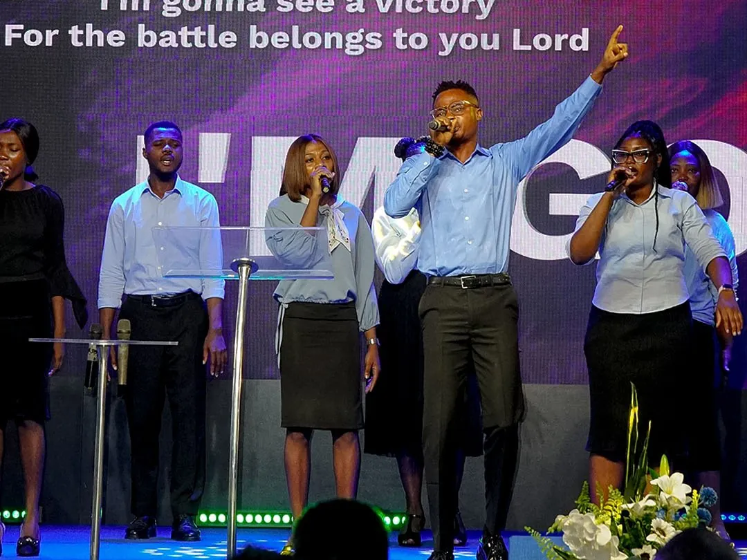 The worship team leading praise on stage, with the words of the song on the screen behind them