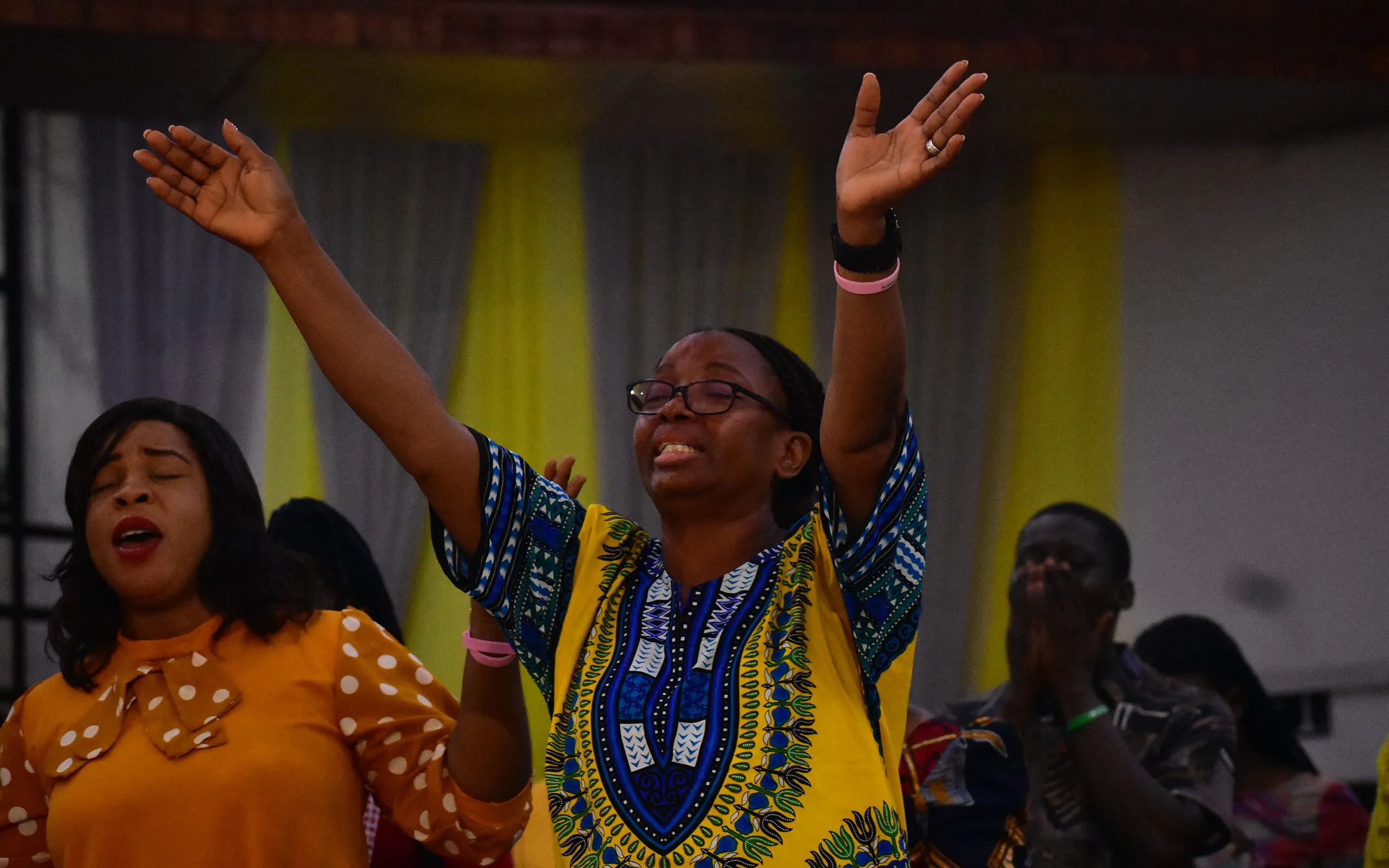 Women worshipping with their hands raised during a service