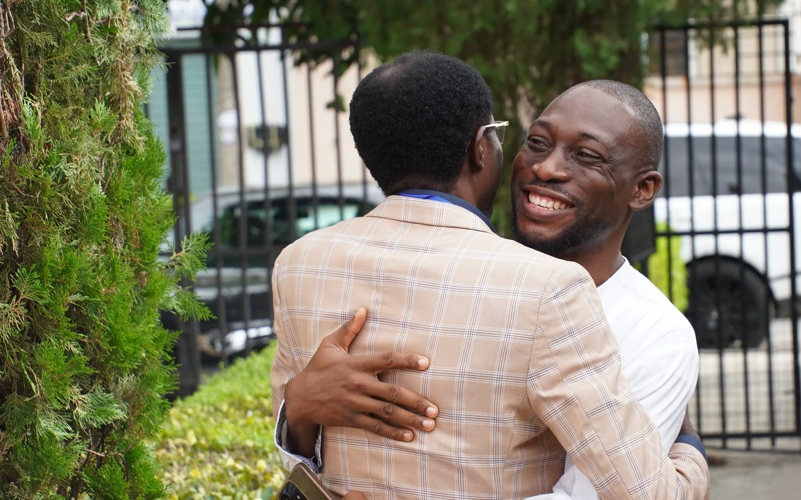 Two members embracing in welcome at the church gate on a Sabbath morning