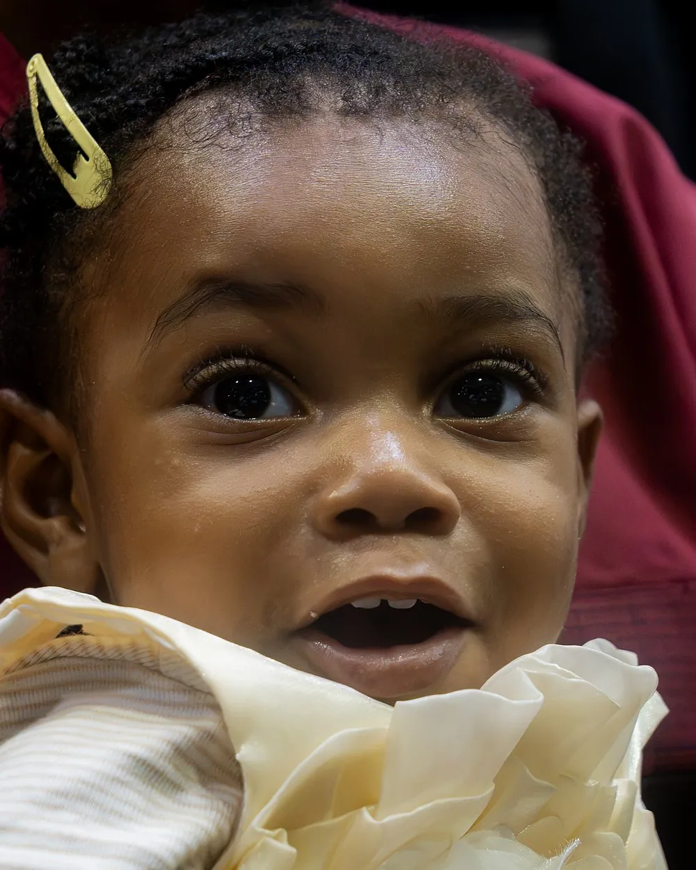 A little girl with a gold hair clip smiling at Sabbath service