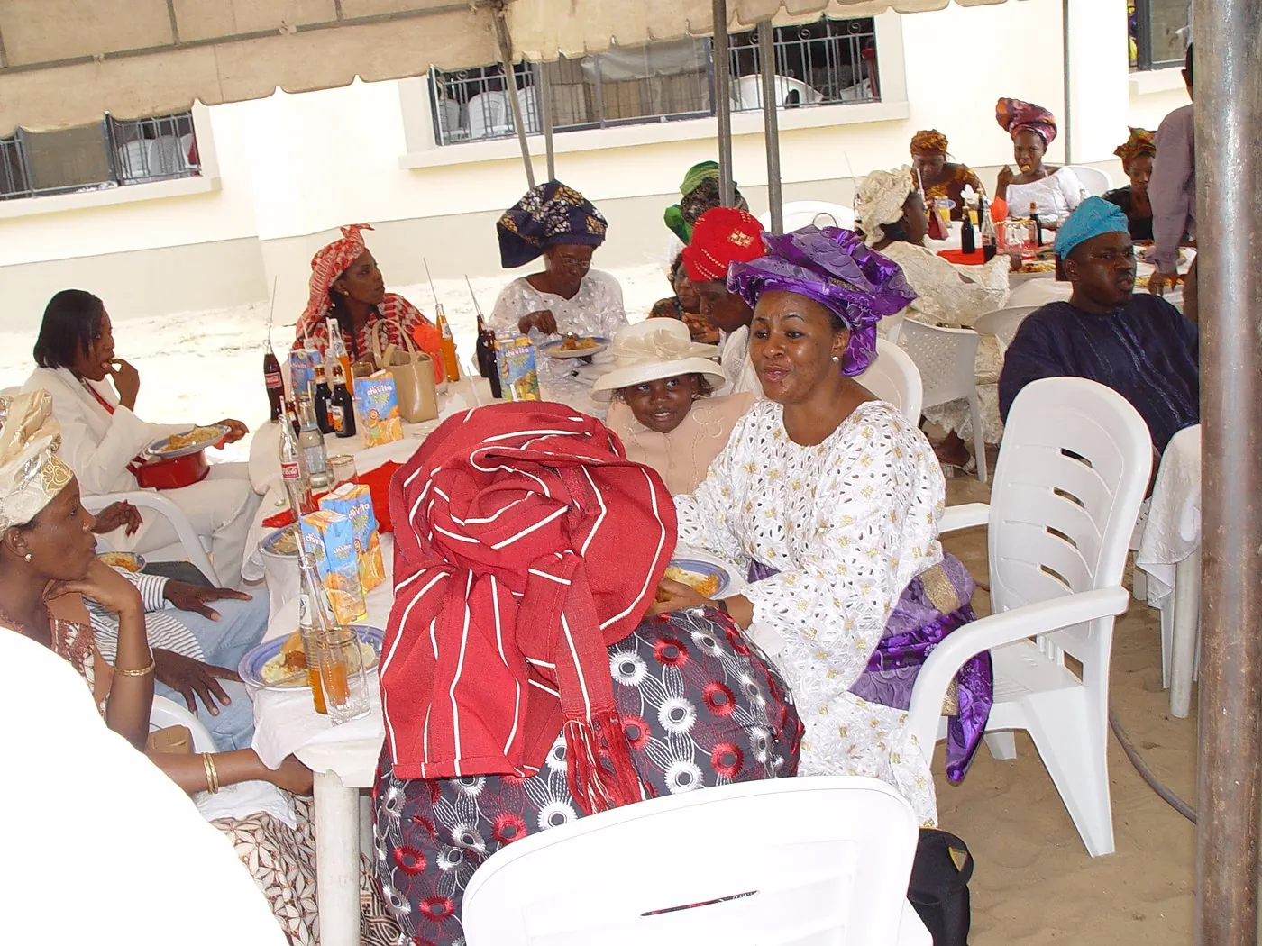 Members talking and sharing a meal together at tables under a canopy
