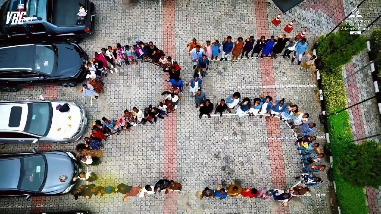 Members standing in the shape of the number 26 in the church grounds, seen from above
