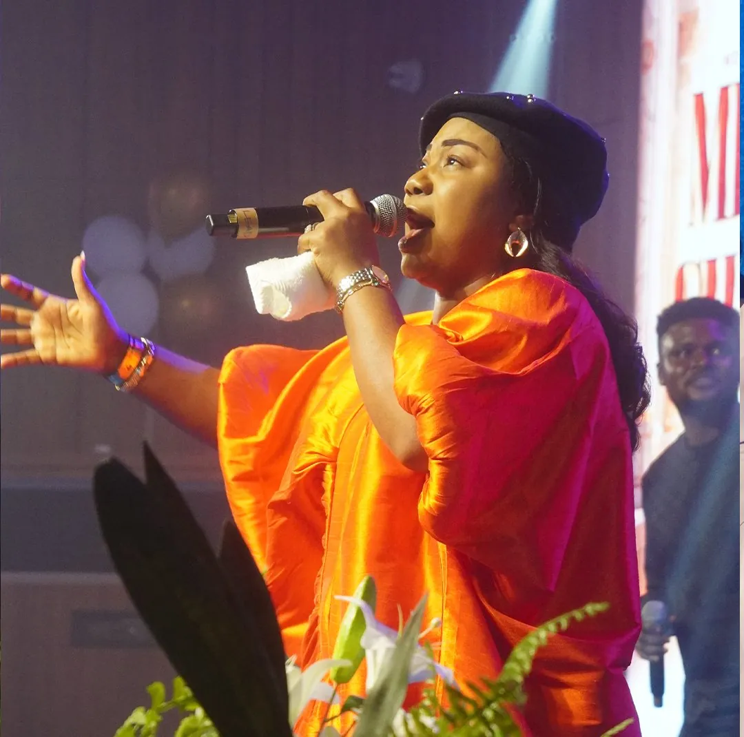 Mercy Chinwo ministering in an orange gown
