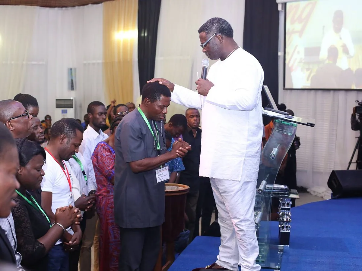 A minister praying over members at the front