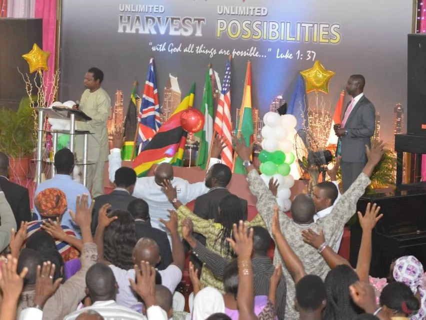 The congregation reaching toward the stage under the Unlimited Harvest backdrop